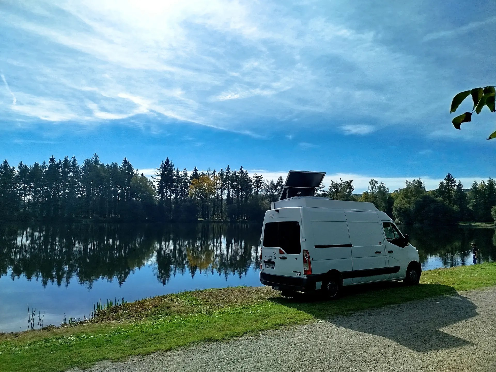 Fourgon aménagé avec tracker solaire 2 axes SunTrek déployé, stationné au bord d’un lac